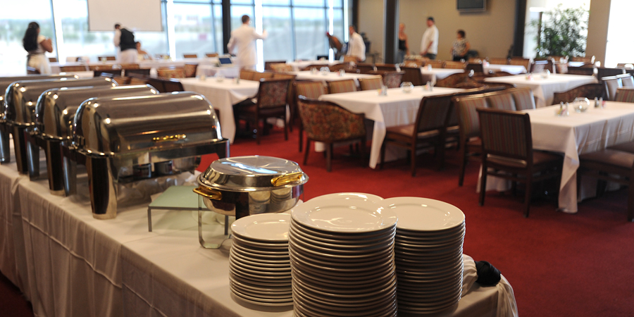A buffet setup featuring silver chafing dishes and stacked plates in an elegantly arranged dining area.