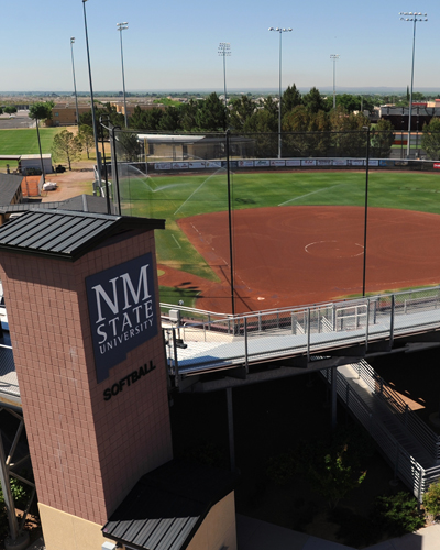 Aerial view of the NM State softball field with the university's logo prominently displayed on a tower structure in the foreground.