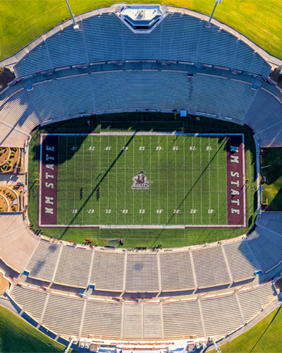 Morning overhead view of the Aggie Memorial Stadium surrounded by green grass.