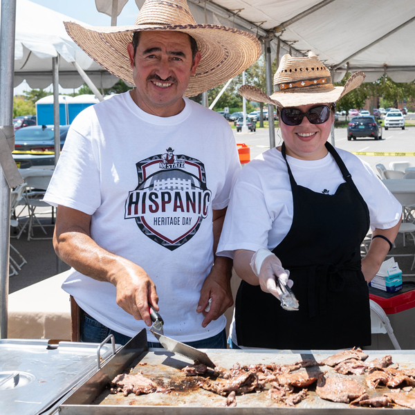 Tailgating NMSU fans grilling meat before a football game.